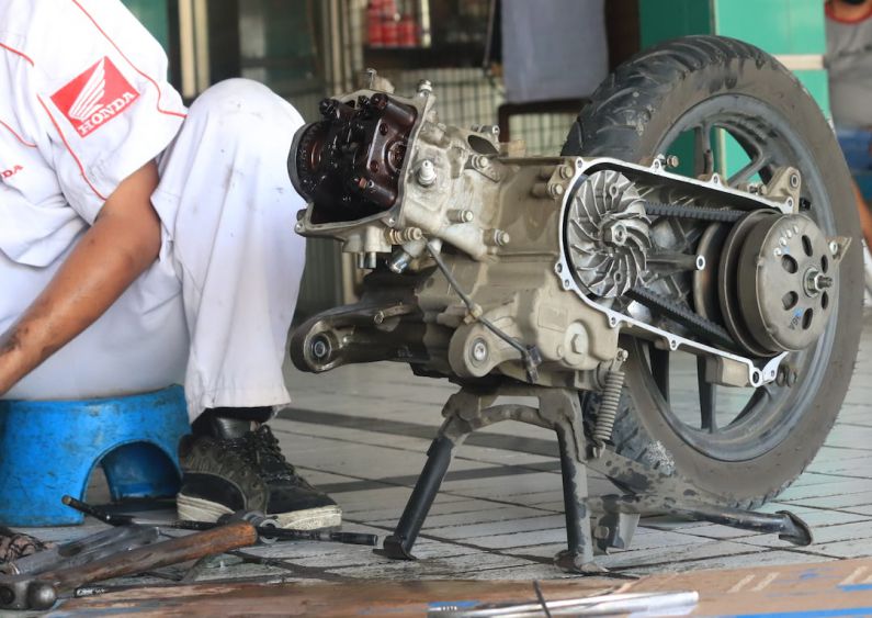 Motorcycle Maintenance - a man is working on a motorcycle engine