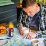 Planning Road Trip - a man sitting at a table with a plate of food and a cup of coffee