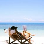Beach Vacation - woman sits on brown wooden beach chair