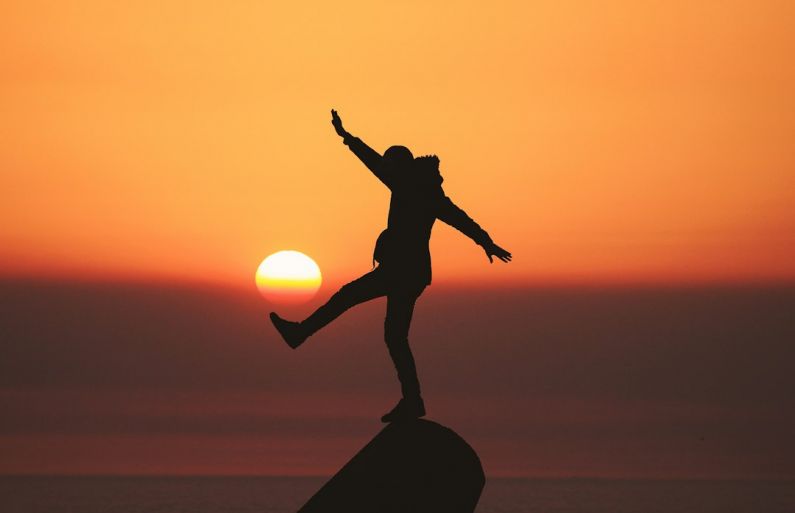 Balancing Life - photo of silhouette photo of man standing on rock