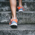 Training Marathon - person wearing orange and gray Nike shoes walking on gray concrete stairs