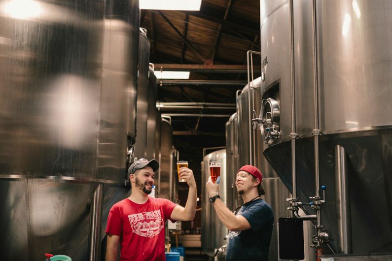 Brewing Beer - two men tasting beer near cylindrical tanks